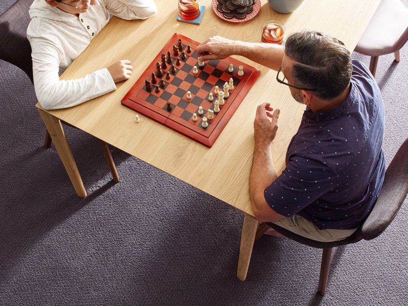 people playing chess at a table in a room with purple carpet from Life Style Floors in Chagrin Falls